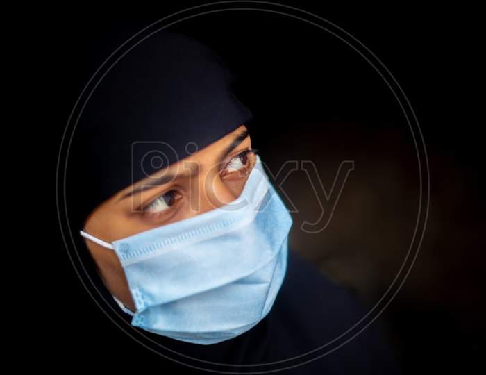 An Asian Muslim Girl Wearing A Surgical Mask For Coronavirus Protection. Black Hijab Woman Wearing A Blue Mask For Safety. Side Views.