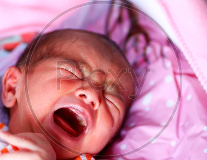 A Newborn Asian Baby Crying With Open Mouth And Closed Eyes