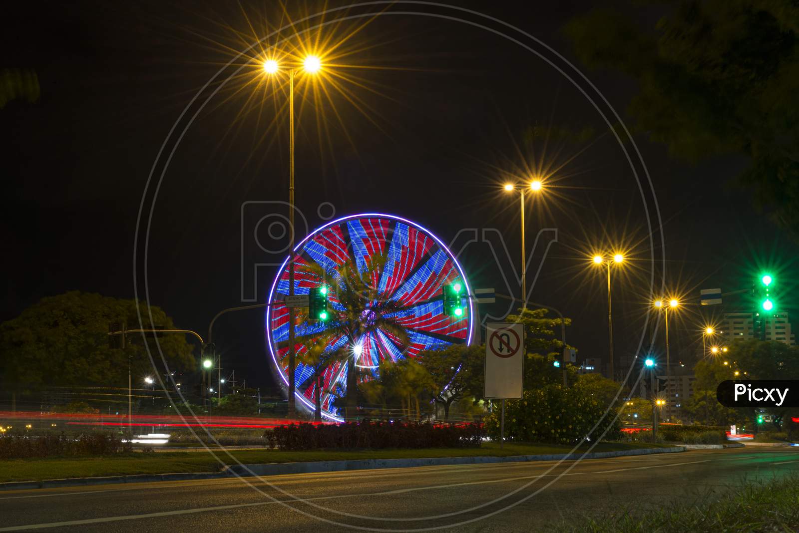 Long Exposure Of Colorful Ferris Wheel And Light Trails On The Expressway Road At Night.