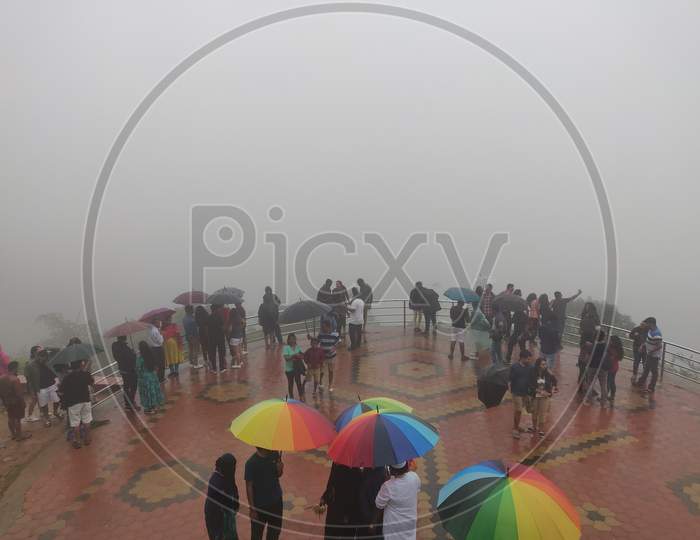 July 6, 2019- Karnataka, India: A Landscape View Of Raja'S Seat Park Filled With Fog In Coorg, Karnataka, India. People Spectating The View.