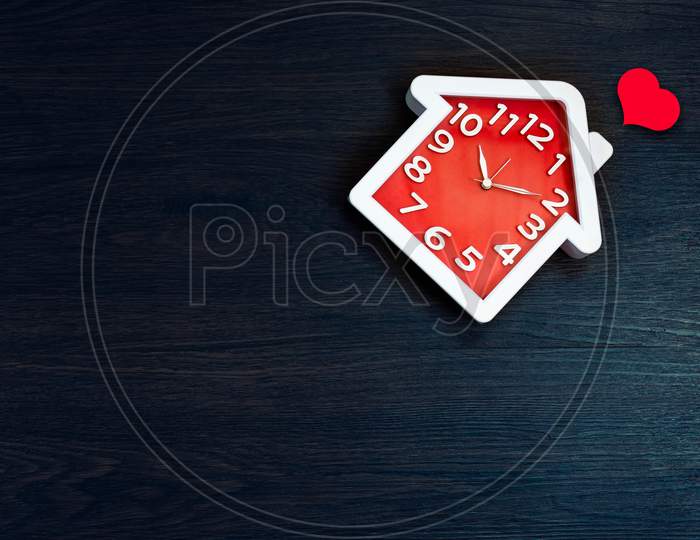 Home Shape Clock On Floor Background With Red Heart Icon. Happy Life And Family Concept. Interior And Object Theme. Time In Daily Life Theme.