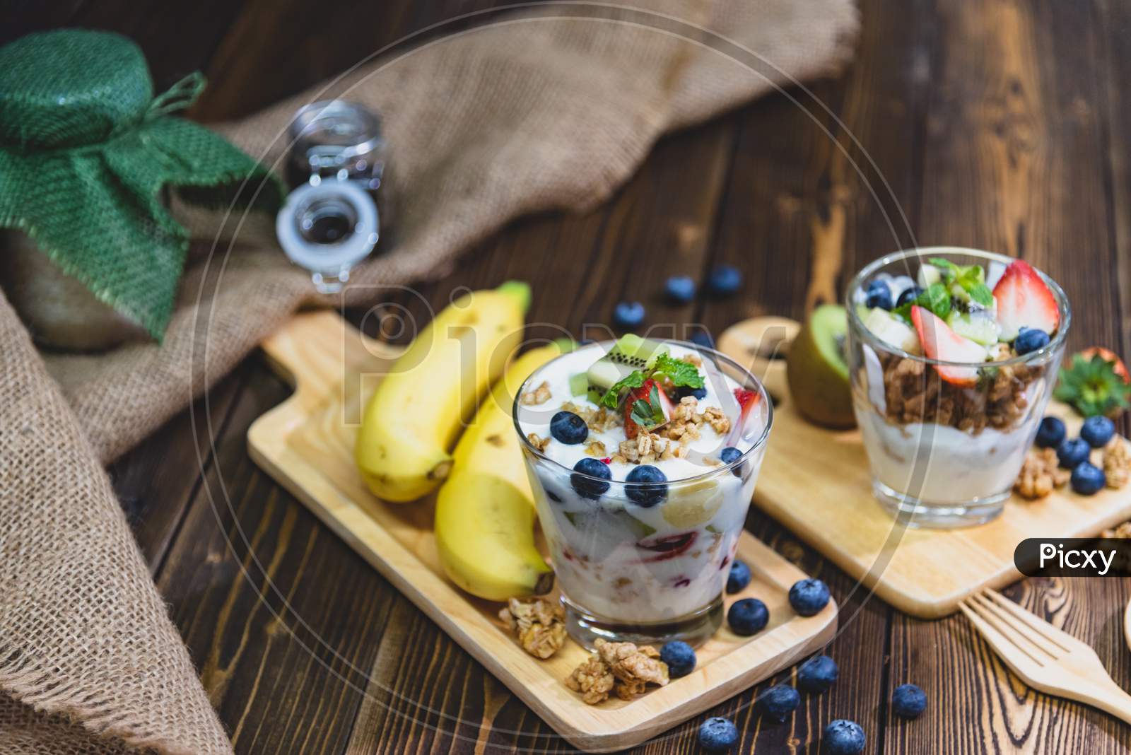 Healthy Greek Yogurt With Granola And Mixed Berries On Wooden Table And Many Fruits. Food And Dessert Concept.