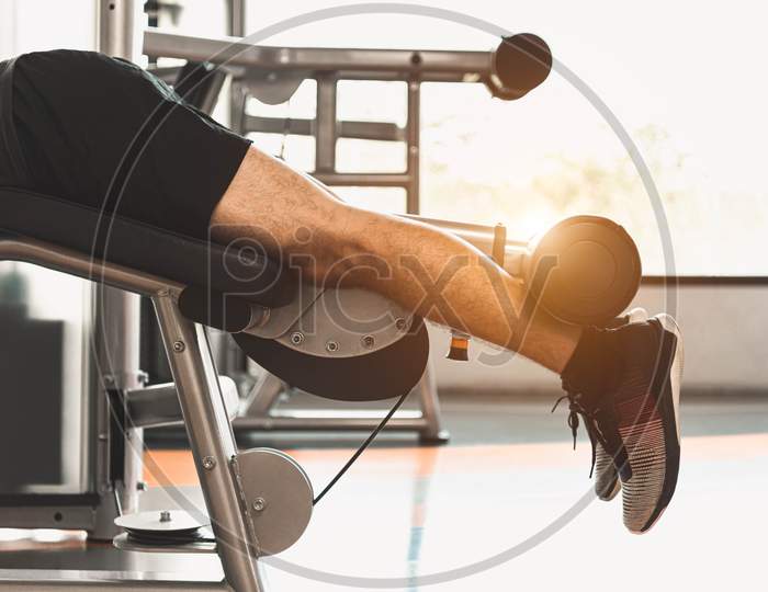 Close Up Of Sport Man Stretching And Lifting Weight By Two Legs When Facing Down For Stretching Muscle At Fitness Gym At Condominium Background. Sport And People Lifestyles Concept.