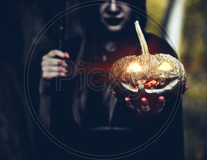 Pumpkin In Witch Hand. Old Woman Holding Pumpkin In Dark Forest. Halloween Day And Mystery Concept. Fantasy Of Magic Theme.