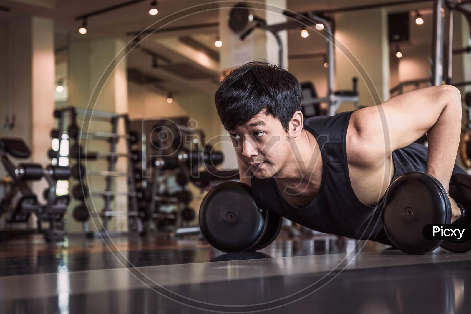 Portrait Of Asian Fitness Man Doing Pushing Up Exercise With Dumbbell In Gym. People Lifestyle And Sport Concept. Sportsman Holding Weight By Two Hands On Floor.