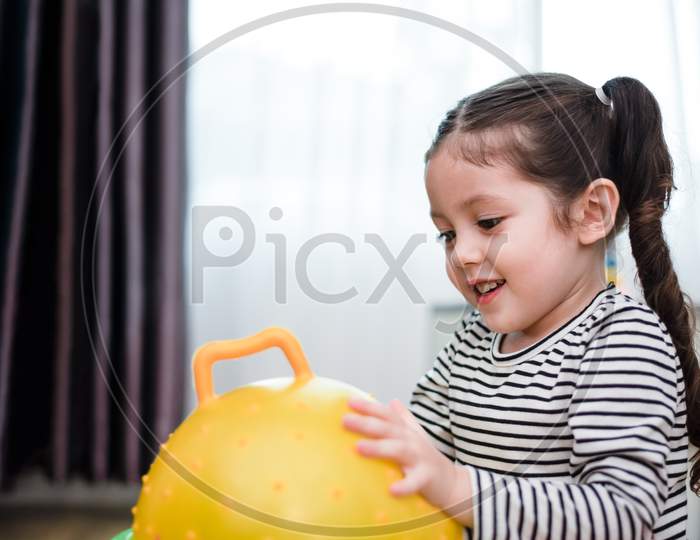 Little Girl Playing Rubber Ball In Home. Education And Happiness Lifestyle Concept. Funny Learning And Children Development Theme.
