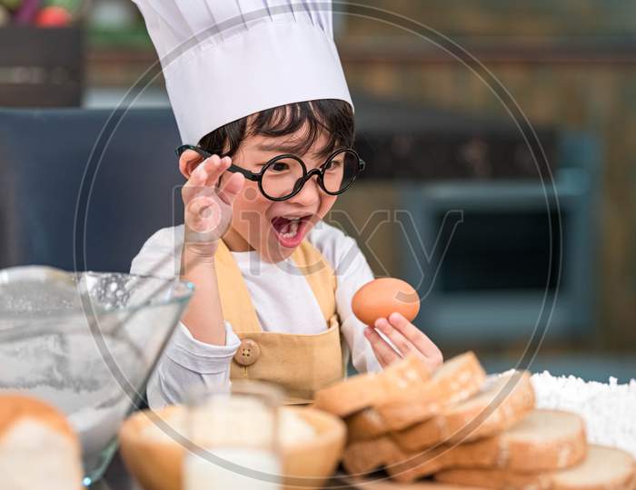 Portrait Cute Little Asian Happy Boy Surprised And Interested In Cooking Funny In Home Kitchen. People Lifestyles And Family. Homemade Food And Ingredients Concept. Baking Christmas Cake And Cookies