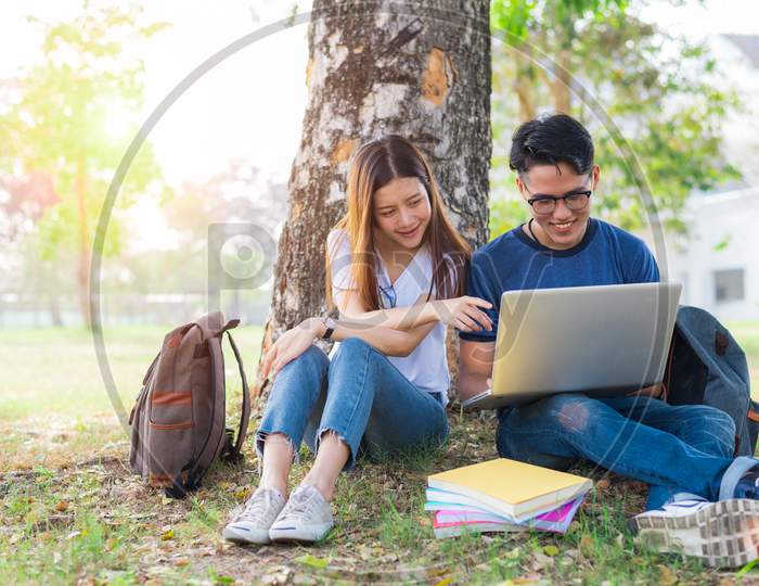 Two Asian Young College People Discussing About Homework And Final Examination For Testing With Laptop. Education And Friendship Concept. Happiness And Learning Concept. Lovers And Friend Theme.
