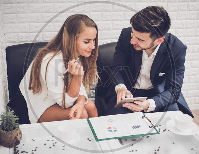 Businessman And Business Woman Analyzing Income Charts And Graphs In Coffee Shop. Business Analysis And Strategy Concept. Indoors Office Theme.