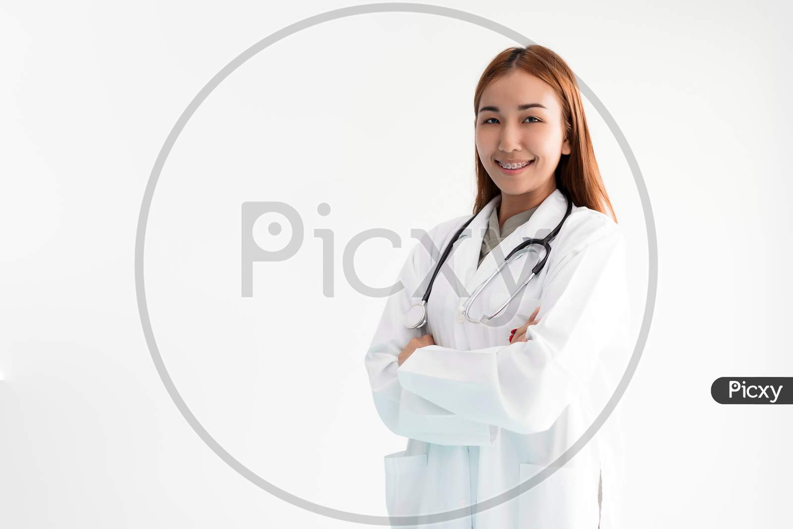 Asian Woman Doctor Is Standing Arms Crossed With Stethoscope On White Background. Medical And Healthcare Concept. Hospital And People Theme.