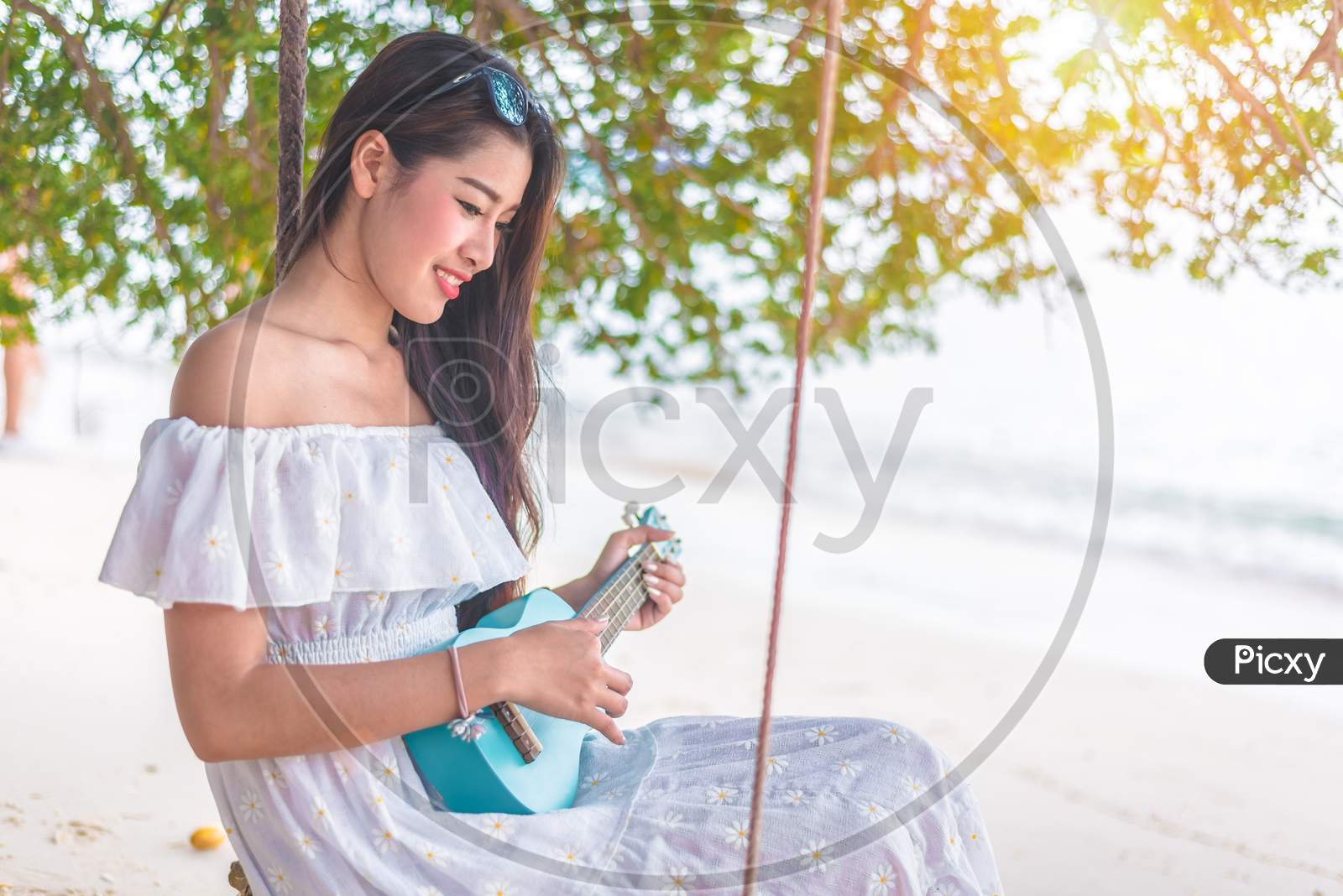 Beautiful Young Asian Woman Playing With Ukulele And Relax On The Beach. People And Holiday Concept. Vacation And Happiness Life Concept. Summer And Beach Theme.