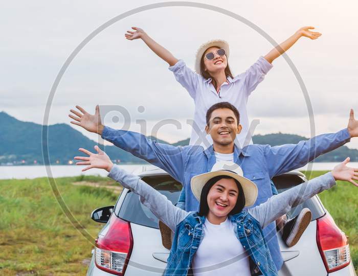 Happy Asian Friends Spread Arms Widely And Breathed Fresh Air With Happiness Mood In On Raod Trip In Car Trunk. People Lifestyle In Long Vacation Trip Concept. Outdoors Nature And Transportation