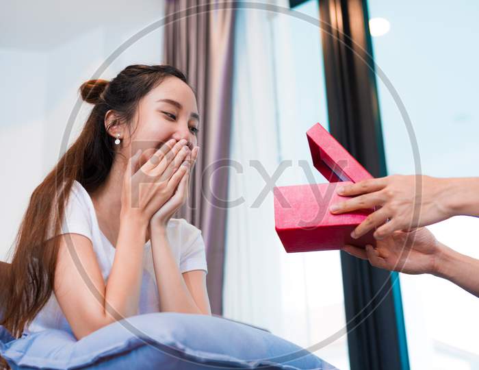 Woman Surprised When Looking At Gift Box On Special Day. Lovers And Honeymoon Concept. Happiness And Valentines Day Theme.