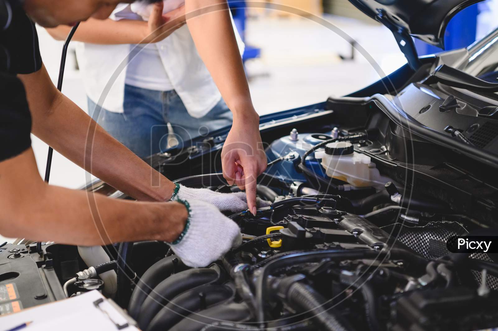 Asian Male Auto Mechanic Examine Car Engine Breakdown Problem In Front Of Automotive Vehicle Car Hood With Female Customer. Safety Technical Inspection Care Check Service Maintenance For Road Trip