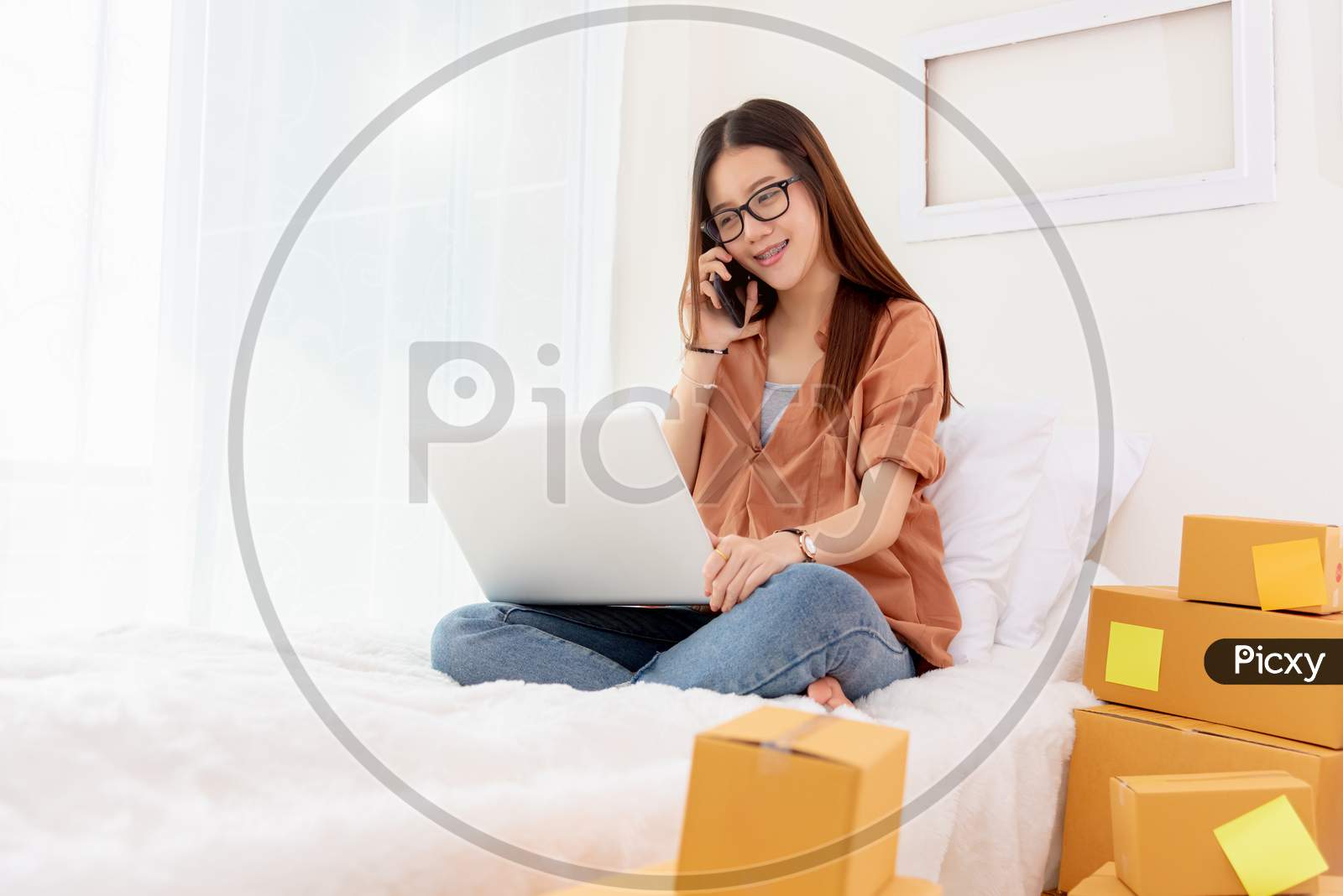 Beauty Asian Woman Using Laptop And Calling Phone On Bed. Business And Technology Concept. Delivery And Online Shopping Concept. Post And Service Theme. People Lifestyle Remote Work In Domestic House