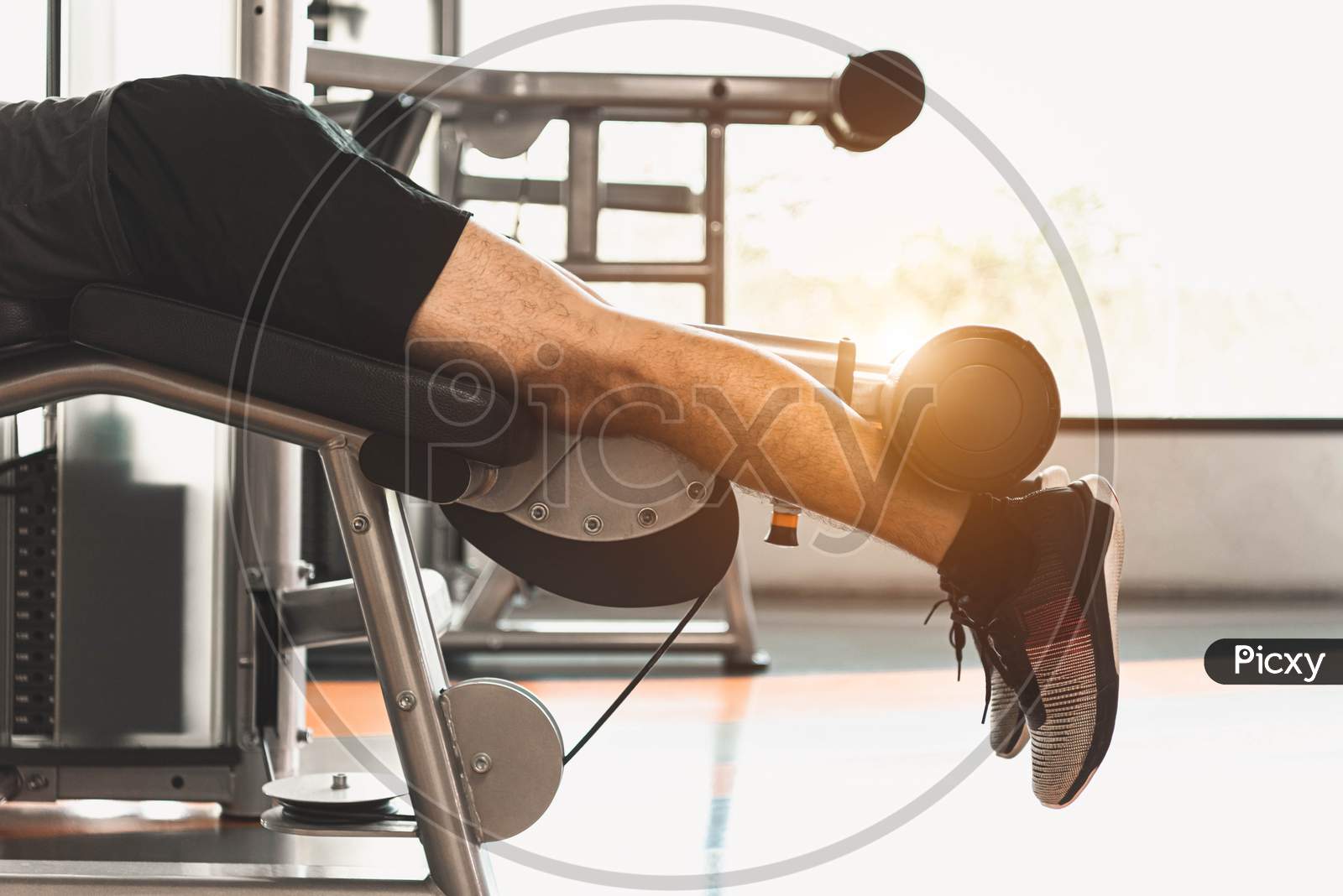 Close Up Of Sport Man Stretching And Lifting Weight By Two Legs When Facing Down For Stretching Muscle At Fitness Gym At Condominium Background. Sport And People Lifestyles Concept.