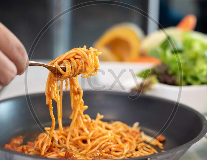 Spaghetti Lifted By Fork With Vegetable Salad And Dish Background. Food And Cousine Concept. Italian Food In Kitchen Theme. Recipe And Menu Theme.