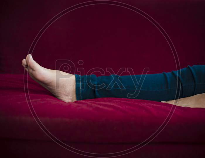 Woman Legs With Wearing Jeans While Relaxing At Movie Theater Or Home At The Red Sofa, Relax And Holiday Concept, Bed Time Sleeping Concept