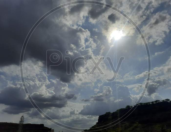 Sun Ray's travelling from dark clouds blue sky behind and small hill at the surface, natural beauty of sky