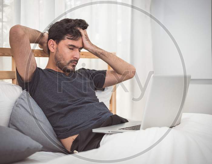 Man Stressed Out From Work With Laptop In Bedroom. Technology And Lifestyle Concept. Social Issues And Problem. Healthcare And Office Syndrome. Economic Downturn And Critical Deadline Crisis Theme.