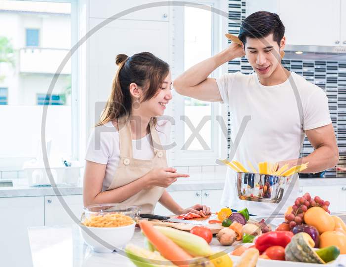 Asian Lovers Or Couples Cooking So Funny Together In Kitchen With Full Of Ingredient On Table. Honeymoon And Happiness Concept. Valentines Day And Sweet Home