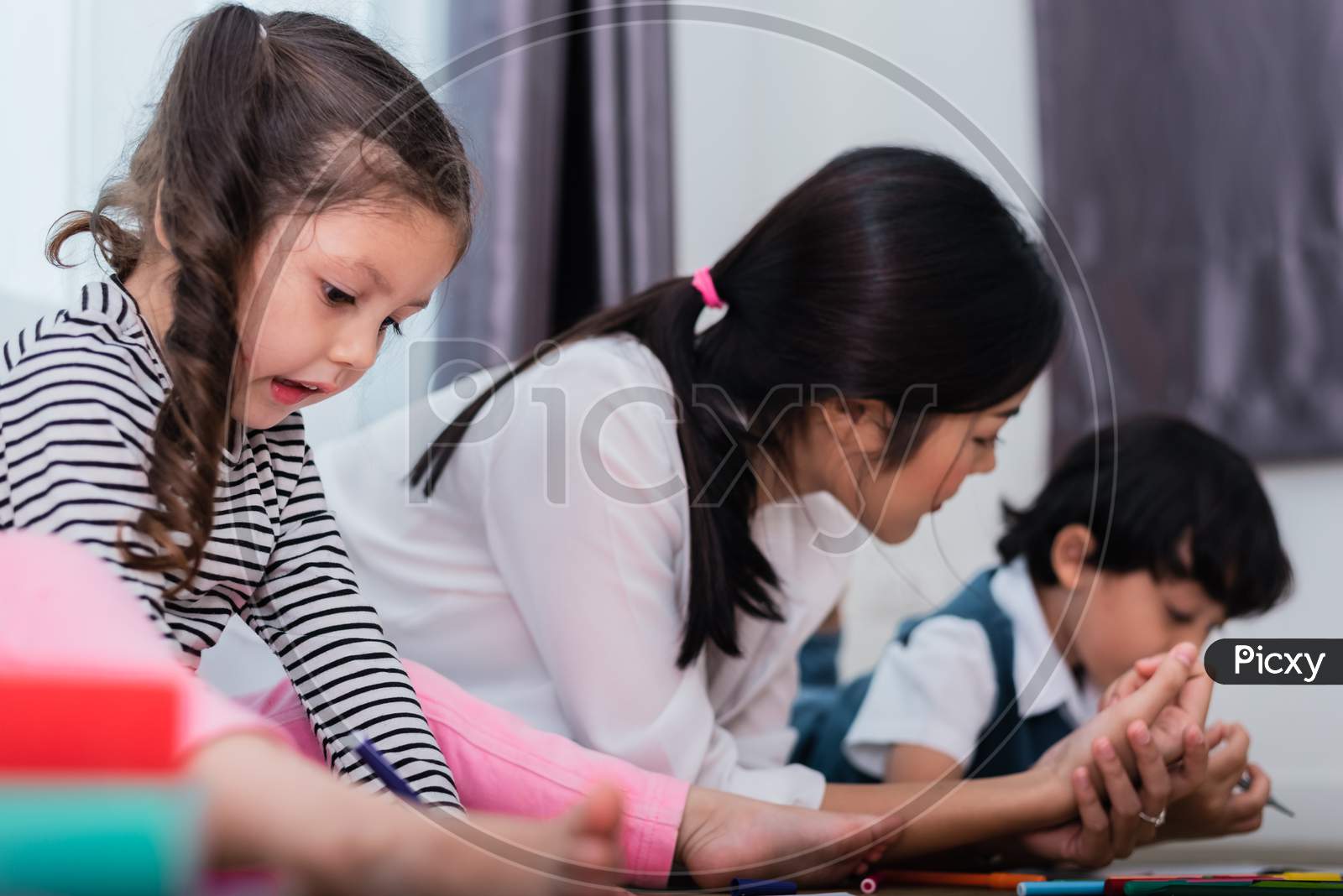 Mother Teaching Children In Drawing Class. Daughter And Son Painting With Colorful Crayon Color In Home. Teacher Training Students In Art Classroom. Education And Learning Development Of Kids Theme.