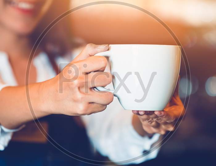 Closeup Of Professional Female Barista Hand Making And Holding White Cup Of Coffee. Happy Young Woman At Counter Bar In Restaurant Background. People Lifestyles And Business Occupation Concept