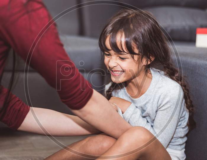 Caucasian Little Girl Tickled By Mother In Living Room. People Lifestyle And Kids Concept.