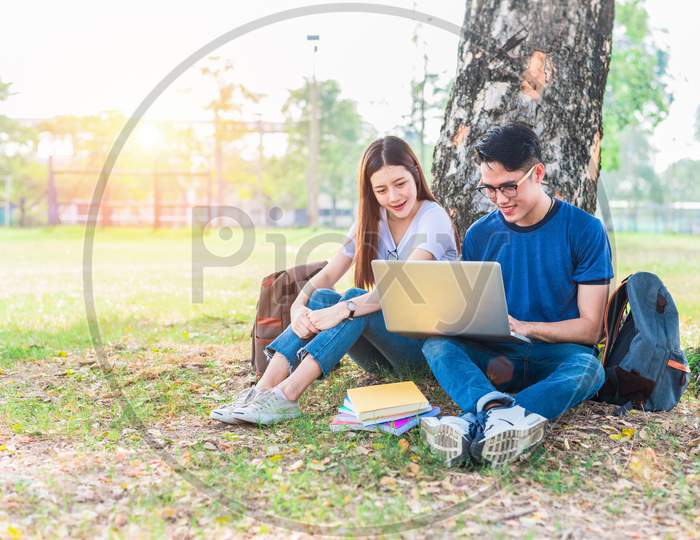 Two Asian Young College People Discussing About Homework And Final Examination For Testing With Laptop. Education And Friendship Concept. Happiness And Learning Concept. Lovers And Friend Theme.