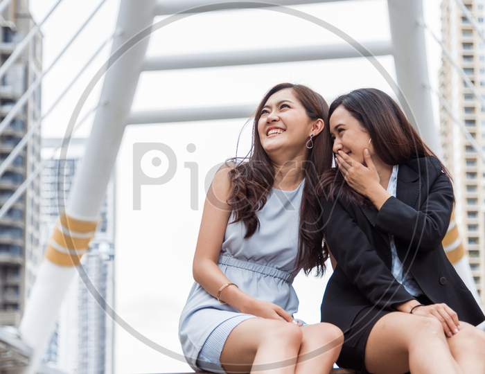 Two Asian Businesswomen Gossip Joke Story At Outdoors City After Finished Working. Business Women Coworker And Friendship Concept. Beautiful Business People Talking Secret Scandal Topic In Office Life