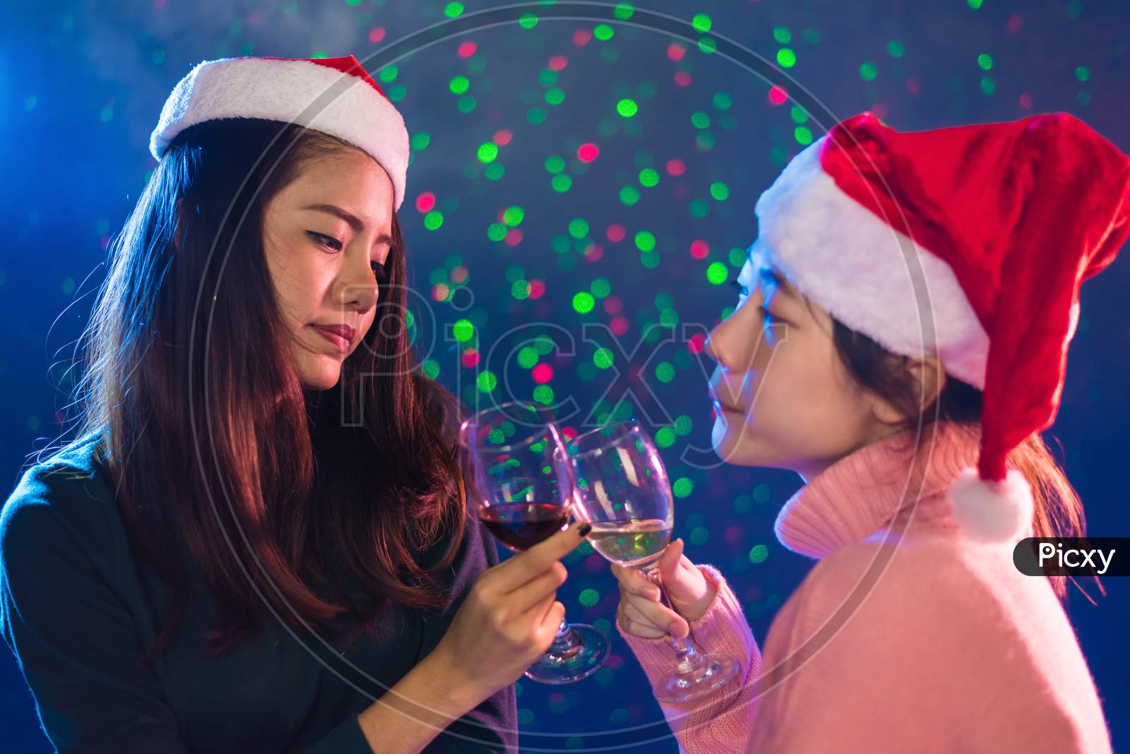 Two Asian Woman Celebrating Christmas And New Year Party With Toasting Wine Glasses In Pub. People And Night Life Concept. Party And Event Theme. Clink Glasses Together
