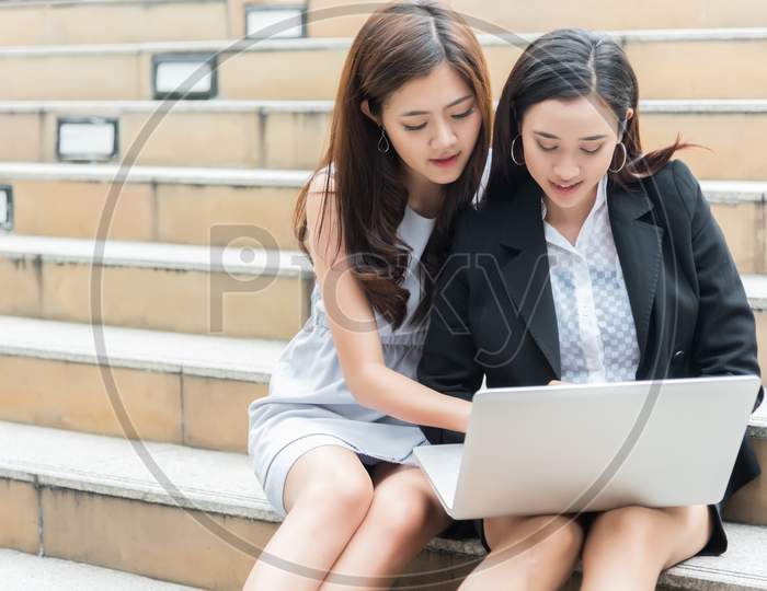 Two Business Women Consulting And Using Laptop At Outdoor, Business And Technology Concept