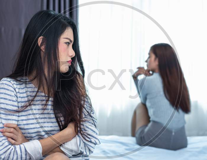 Asian Woman Having Stressed After Conflict With Girlfriend In Bedroom. Serious And Negative Thinking People. Upset And Unhappy Female Concept. Lifestyle And Family Issues. Lgbt Theme