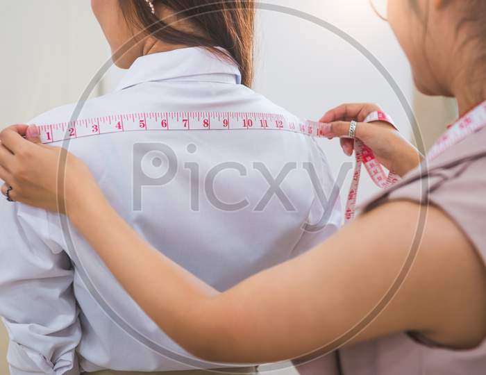 Dressmaker Measuring Female Customer Shoulder In Sewing Atelier Workshop Office. Tailor And Fashion Designer Concept. Job And Freelance Occupation. Business People In Clothing Shop