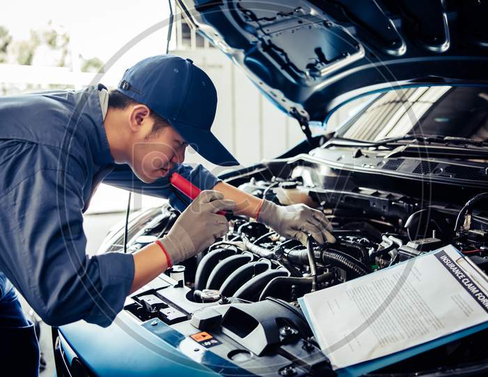 Car Mechanic Technician Holding Flashlight Checking Engine With Checklist Clipboard To Maintenance Vehicle By Customer Claim Order In Auto Repair Shop Garage Repair Service. People Occupation Business