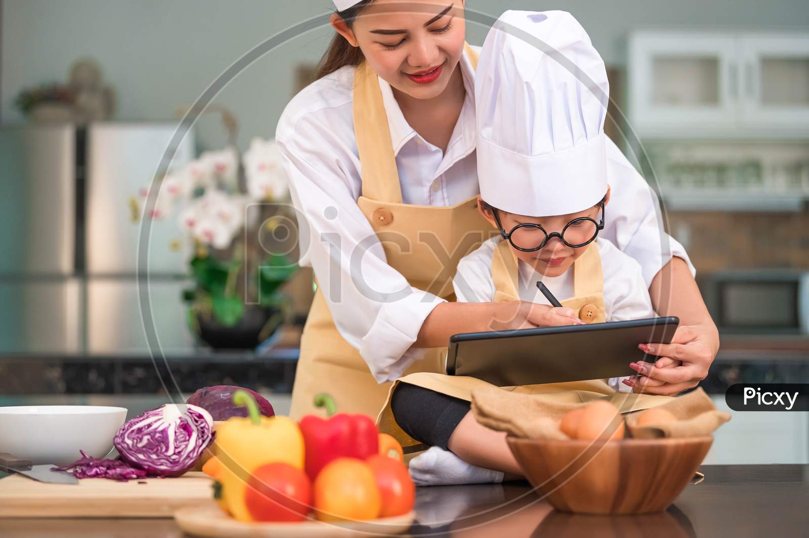 Asian Beauty Mother And Cute Little Boy Prepare Online Shopping And Listing Ingredient For Cooking In Kitchen At Home With Tablet. People Lifestyles And Family. Homemade Food And Ingredient Concept