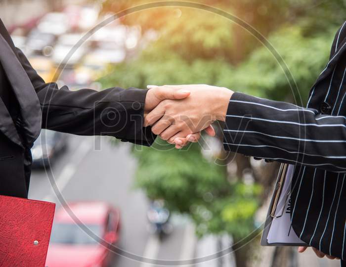 Two Business Women Hand Shake At Outdoors With Traffic Background, Business And Contact Agreement Concept