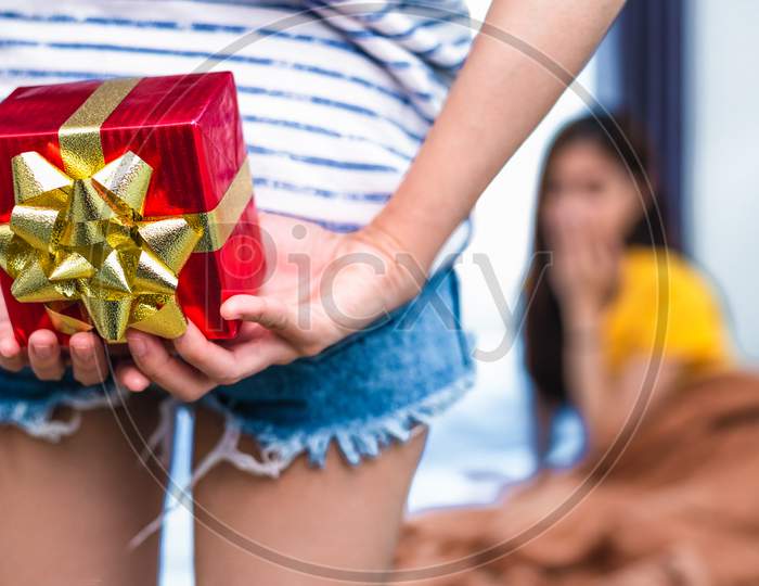 Close Up Of Woman Hands Holding Gift For Surprise Her Girlfriend In Bedroom. Person And People Concept. Lifestyles And Happiness Life Concept. Lesbian And Homosexual Theme.