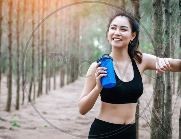 Asian Beauty Woman Drinking Water In Forest. Sport And Healthy Concept. Jogging And Running Concept. Relax And Take A Break Theme. Outdoors Activity Theme.
