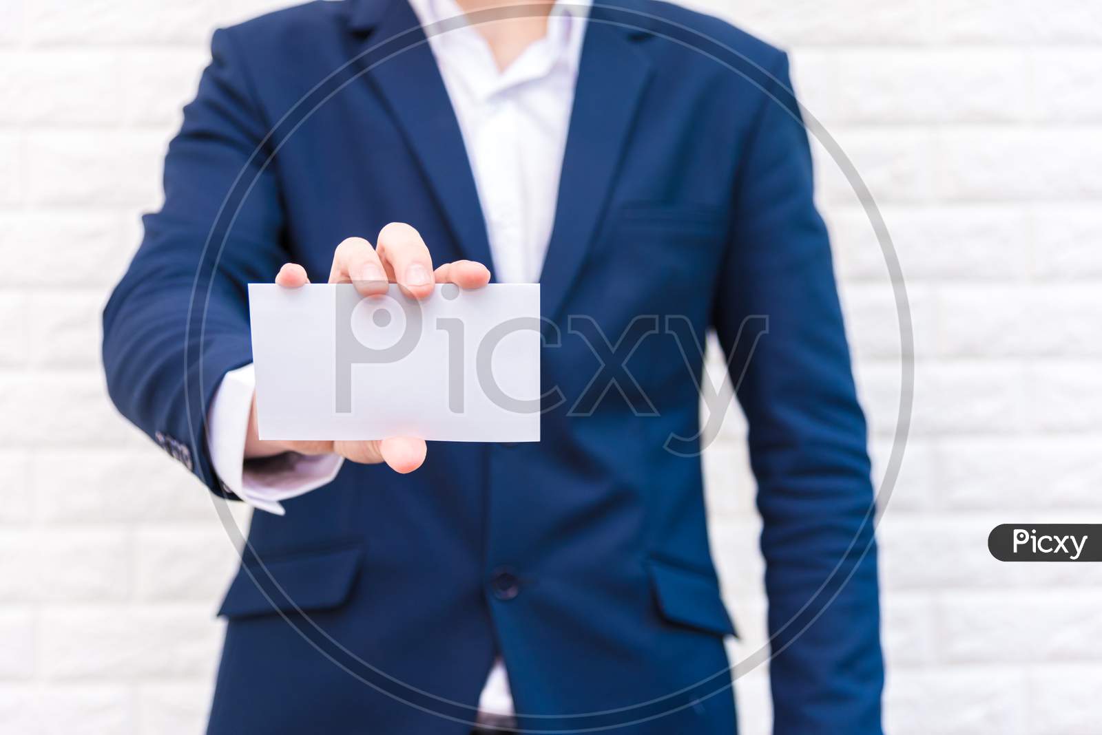 Business Man Showing White Paper. Man  Wearing Blue Suit And Holding White Blank Card. Lifestyle And Working Concept. Business And Object Theme. Blank Space In Paper For Insert Text.