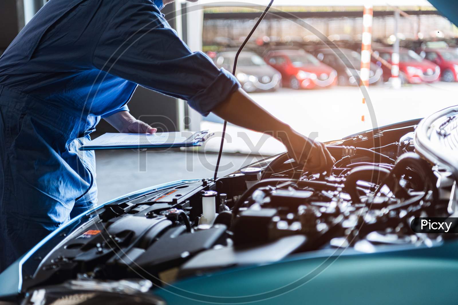Car Mechanic Holding Clipboard And Checking To Maintenance Vehicle By Customer Claim Order In Auto Repair Shop Garage. Engine Repair Service. People Occupation And Business Job. Automobile Technician