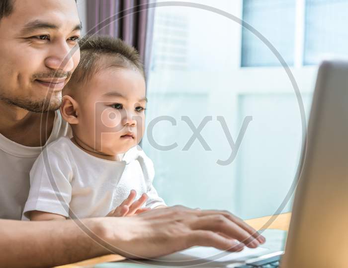 Single Dad And Son Using Laptop Together Happily. Technology And Lifestyles Concept. Happy Family And Baby Theme.