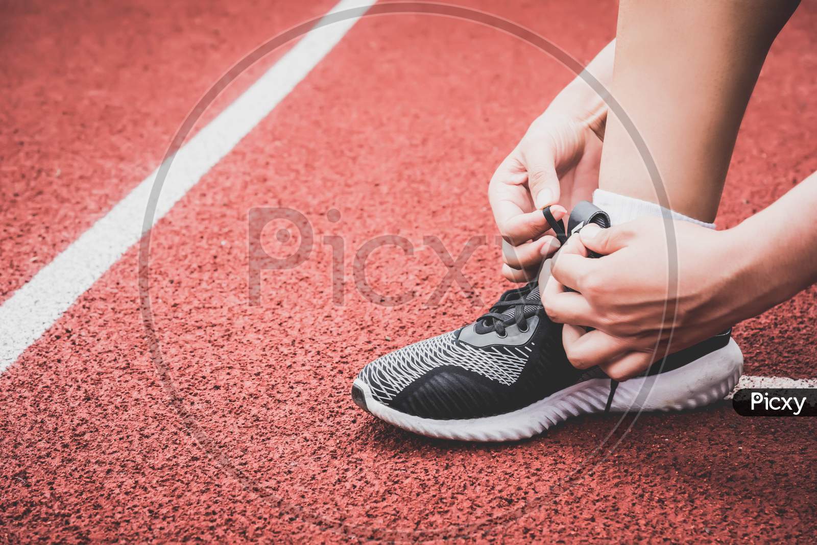 Closeup Of Sport Woman Tying Sneakers Shoelace Rope At Running Track Lane In Stadium. Sport Center And Fitness Gym Concept. Healthy And Body Build Up Theme. Sportswear And Fashion Theme