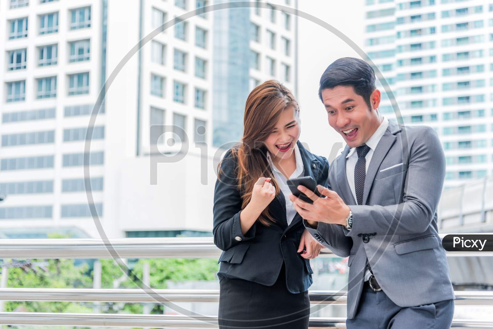 Businessman And His Secretary Are Surprising When Look At The Smartphone, Business Concept, Happiness Concept, Technology Concept.