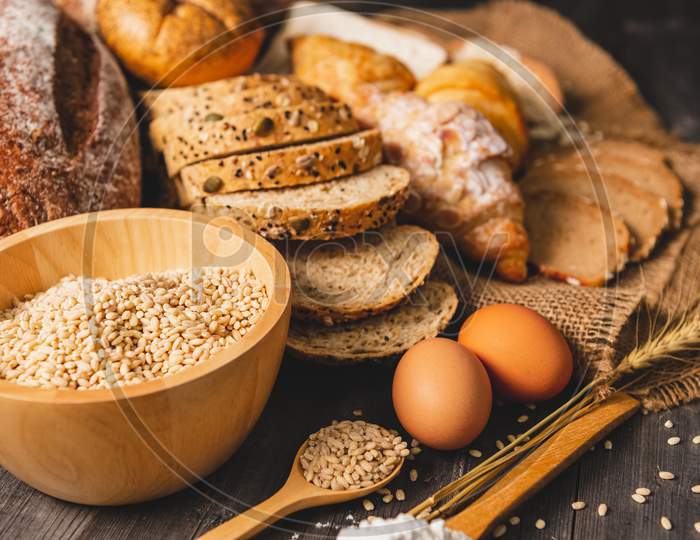 Different Kinds Of Bread With Nutrition Whole Grains On Wooden Background. Food And Bakery In Kitchen Concept. Delicious Breakfast Gouemet And Meal.