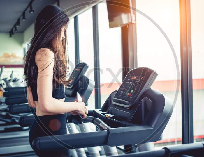 Asian Woman Using Smart Phone When Workout Or Strength Training At Fitness Gym On Treadmill. Relax And Technology Concept. Sports Exercise And Health Care Theme. Happy And Comfortable Mood.