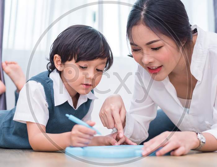 Asian Mom Teaching Cute Boy To Drawing Red Heart In Board With Color Pen. Back To School And Education Concept. Family And Home Sweet Home Theme. Preschool Kids Theme. Front View Angle
