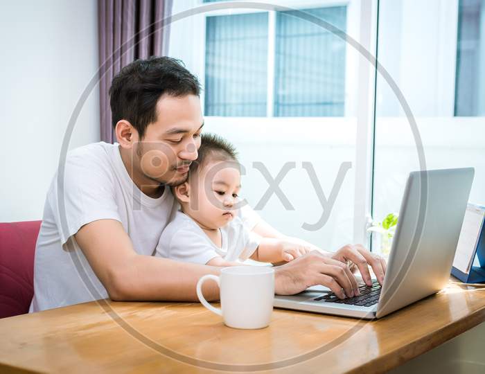 Single Dad And Son Using Laptop Together Happily. Technology And Lifestyles Concept. Happy Family And Baby Theme.
