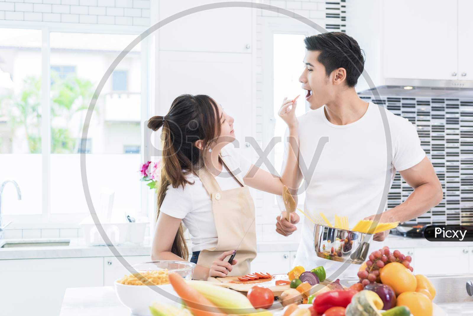 Asian Lovers Feeding Fruit And Food To Each Other, Couple And Family Concept. Honeymoon And Holidays Theme. Indoor Interior