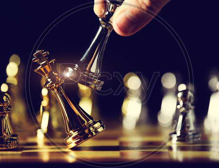 Closeup King Chess Piece Defeated Enemy Or Trade Competitor By Checkmate At End Of Chessboard Game. Businessman Moving Chess To Success Competition By Hand. Leadership And Strategy Management